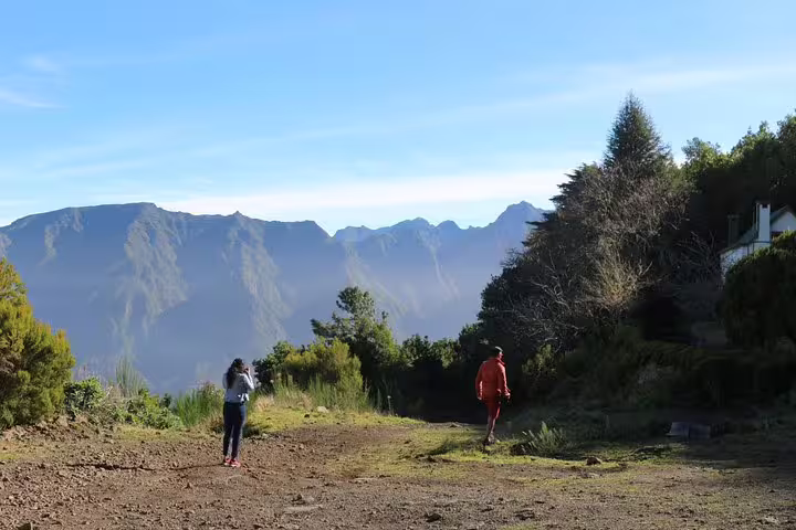 Hikers explore a scenic trail with panoramic views of lush mountains during the West volcanic pools & Unesco 4x4 Tour.