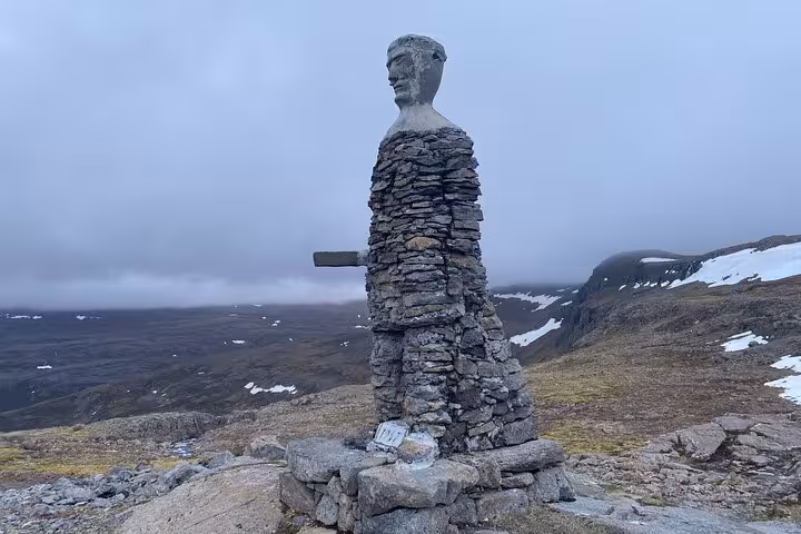 Stone cairn sculpture of a human figure on a rocky hilltop in the Westfjords of Iceland