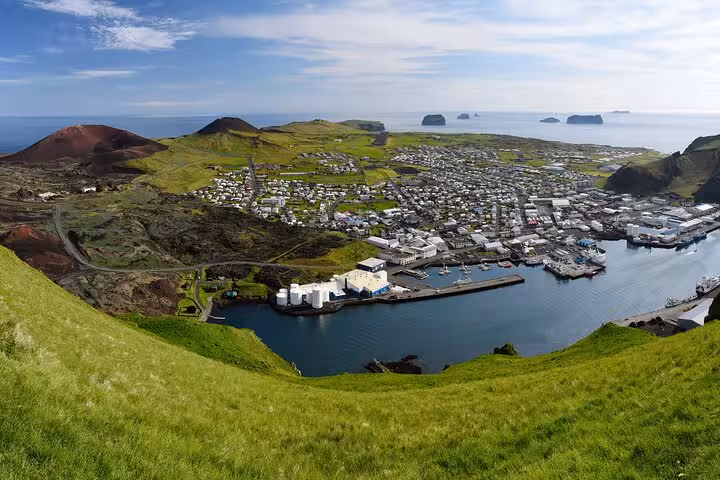 Aerial view of Westman Islands town with harbor, volcanic hills, and ocean in background, Iceland
