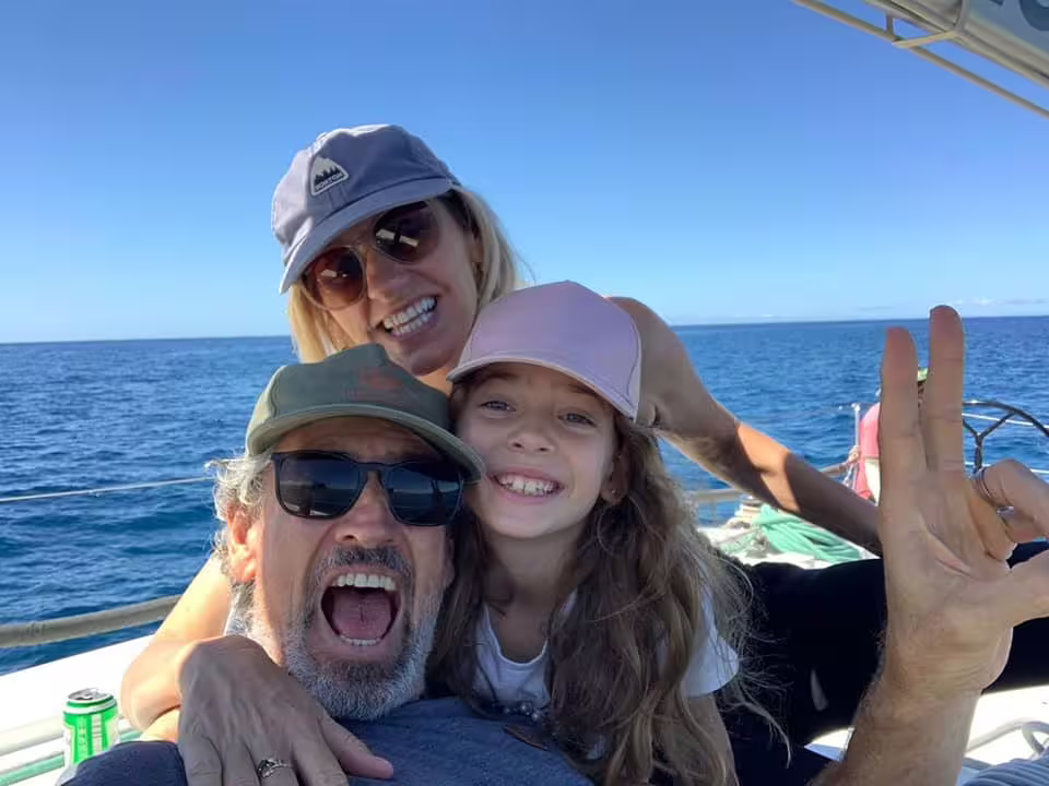 Family enjoying a sunny day on a yacht during a whale and dolphin watching trip in Puerto Colón's serene waters.