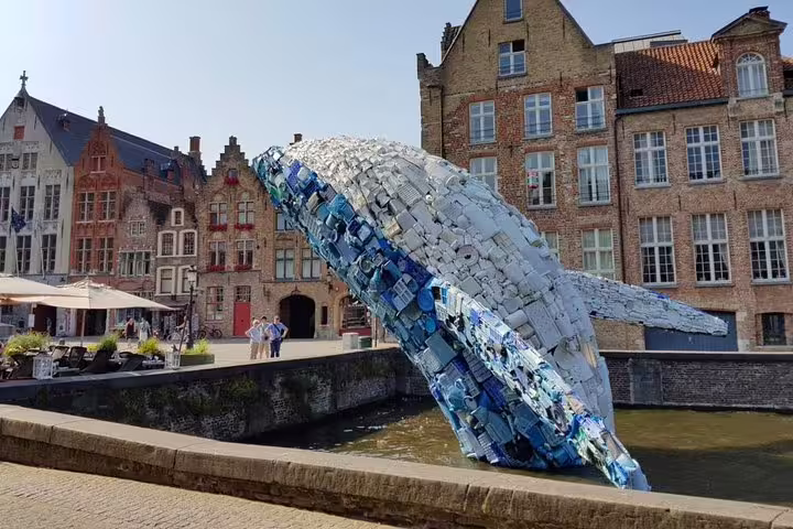 Colorful whale sculpture in Bruges canal by historic houses, perfect stop on a self-guided e-scavenger hunt