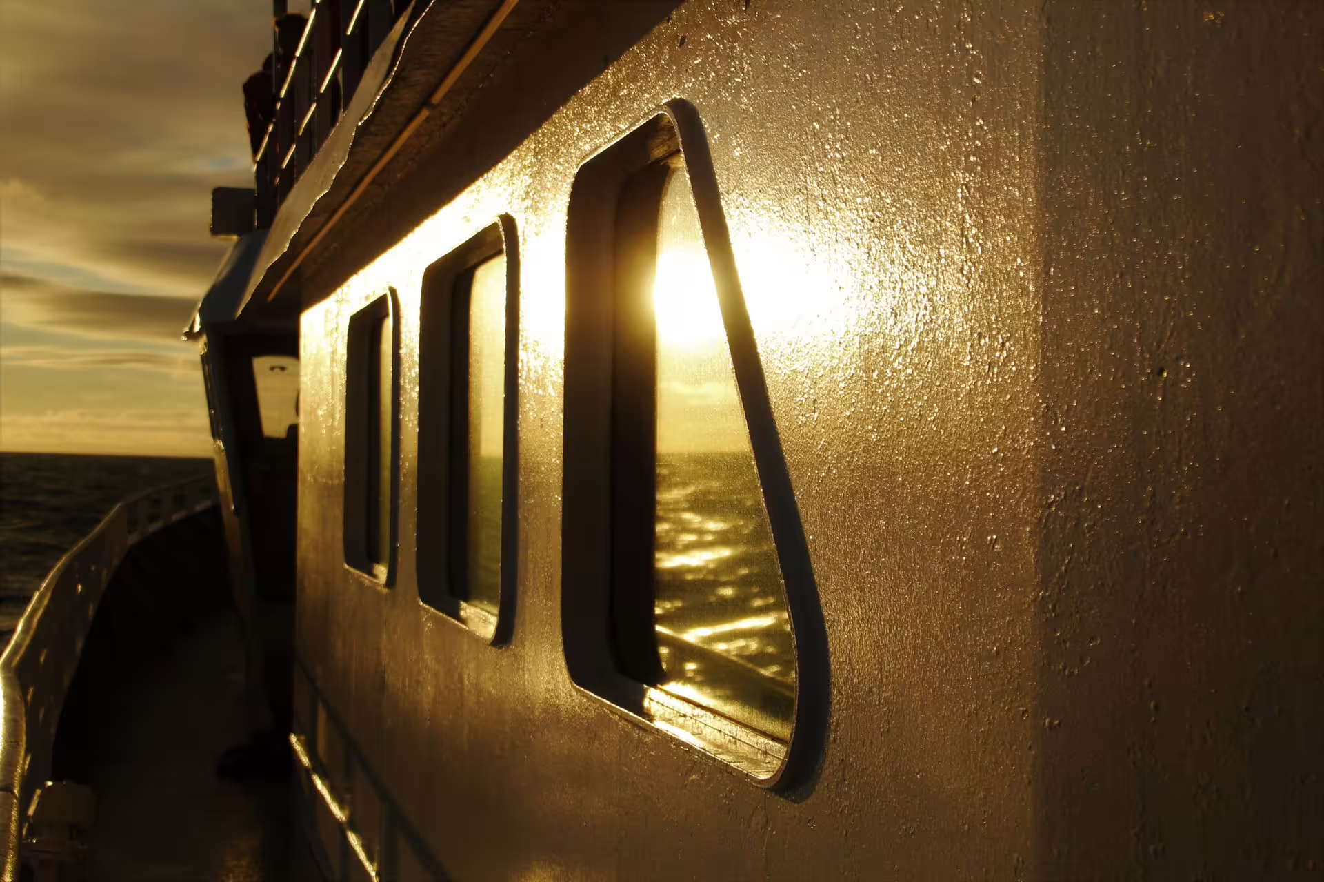 Golden midnight sun reflecting off a whale watching boat hull and windows in Reykjavik ocean waters