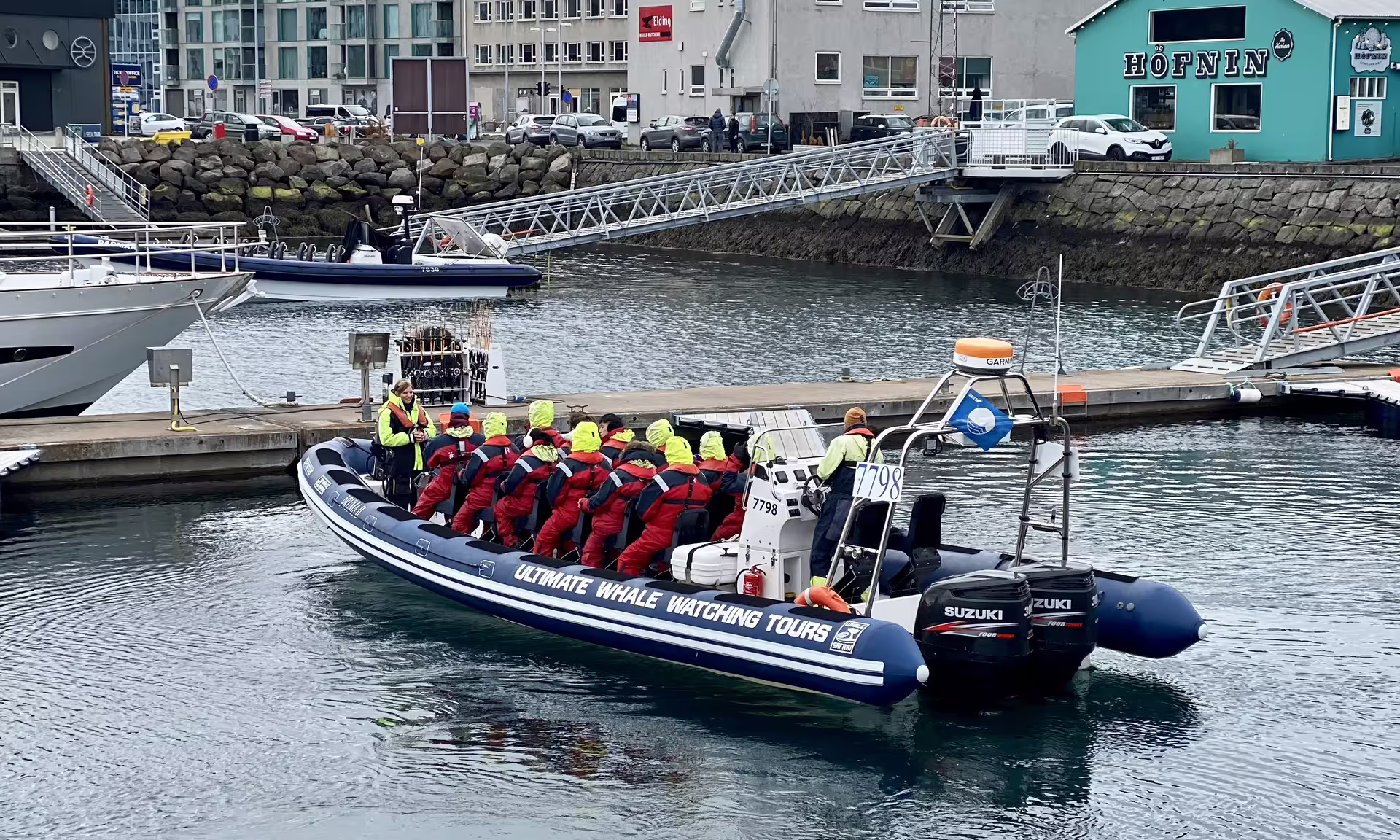 Whale watching RIB boat with passengers in red survival suits departing Reykjavik harbor