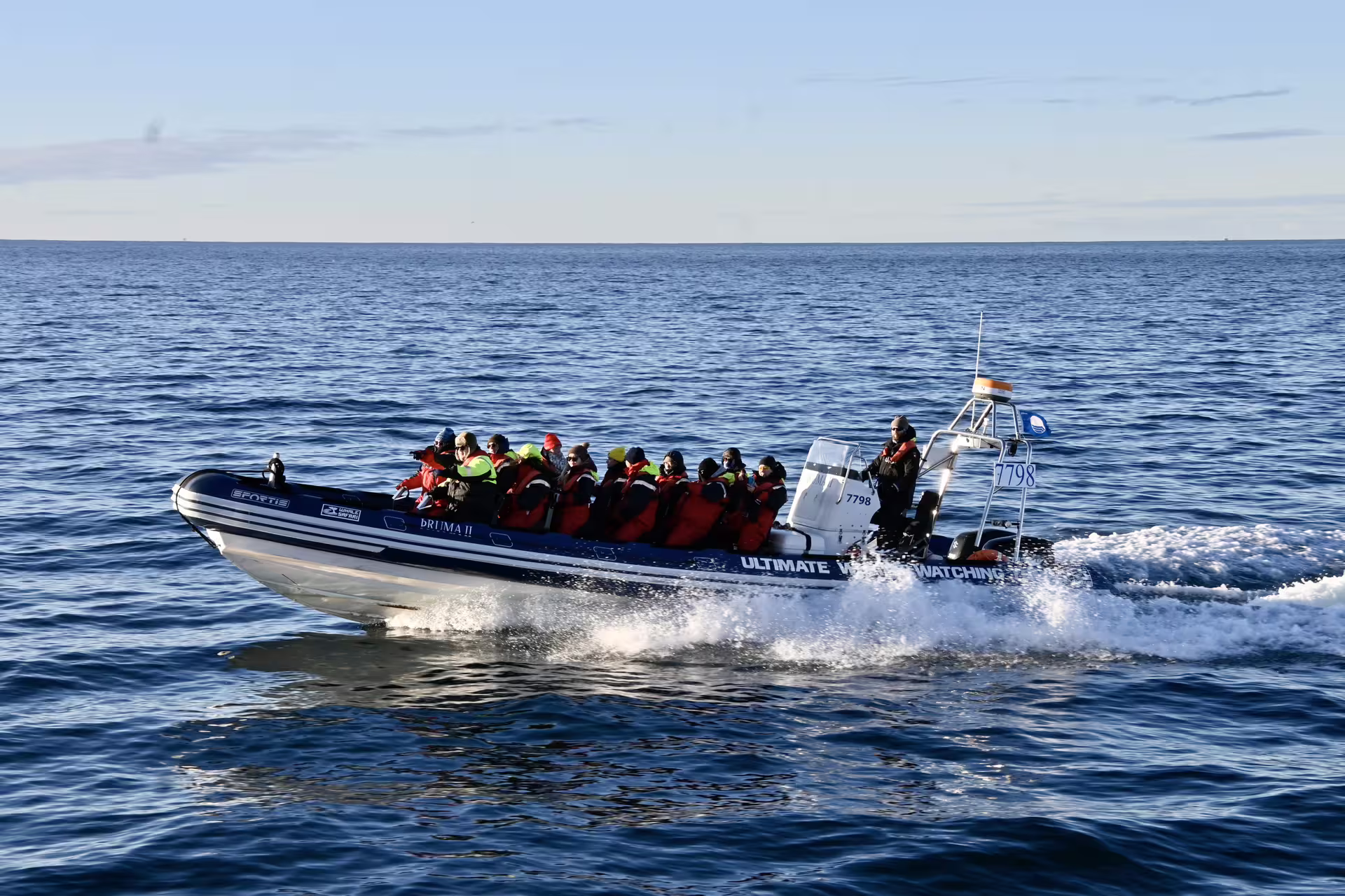 Group of tourists in red life jackets on Ultimate Whale Watching RIB speedboat in Reykjavik waters