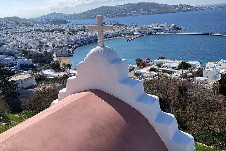 White chapel roof with cross above Mykonos Town and harbor, scenic stop on a private Mykonos highlights tour