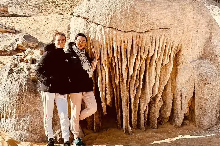 Tourists posing by unique White Desert rock formation on Bahariya Oasis overnight camping tour, Egypt