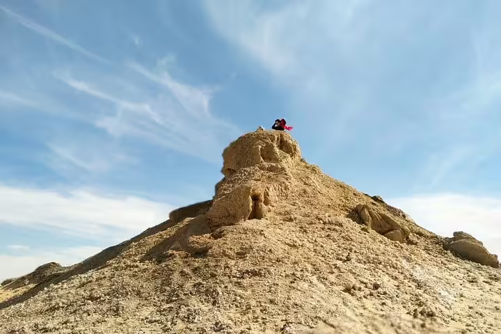 Traveler atop White Desert chalk rock formation in Bahariya Oasis on overnight camping desert safari Egypt