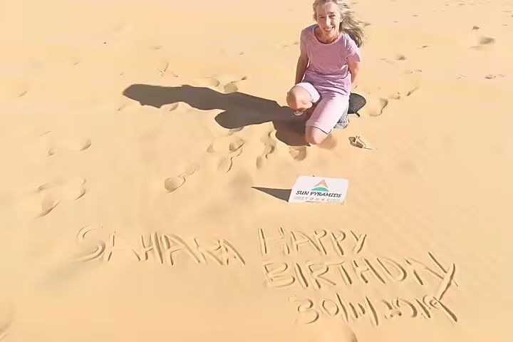 Traveler in Bahariya sand dunes during private White Desert day tour, birthday message written in the sand