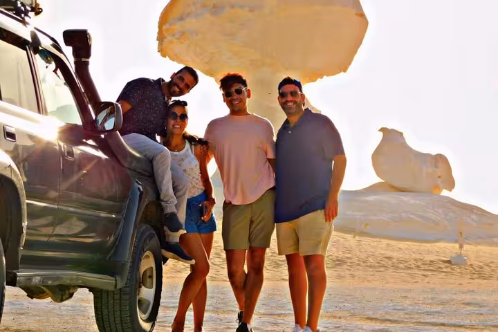 Friends by 4x4 under mushroom rock in White Desert, Egypt, on 3-day desert camping tour with Black Desert and Djara Cave