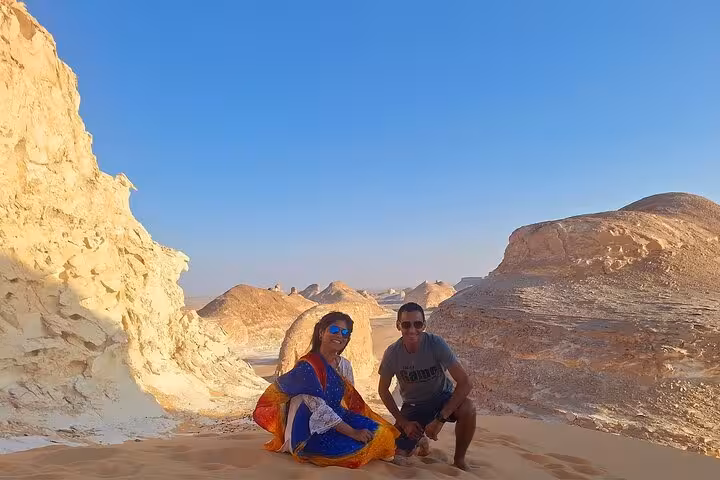 Travelers enjoy a sunny day in the stunning White Desert landscape, surrounded by unique rock formations and sand dunes.