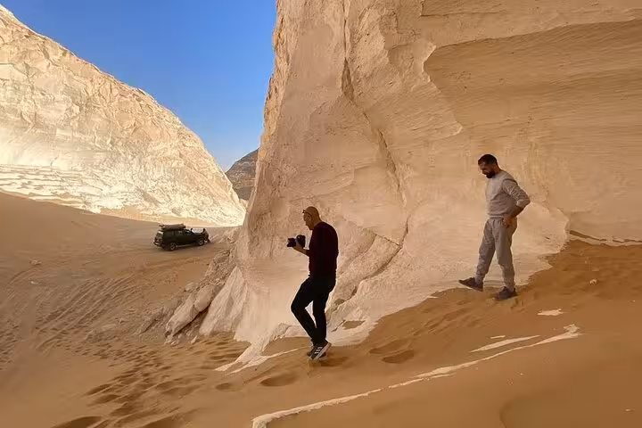 Travelers hiking past chalk cliffs in the White Desert on 3-day camping trip to Black Desert and Djara Cave