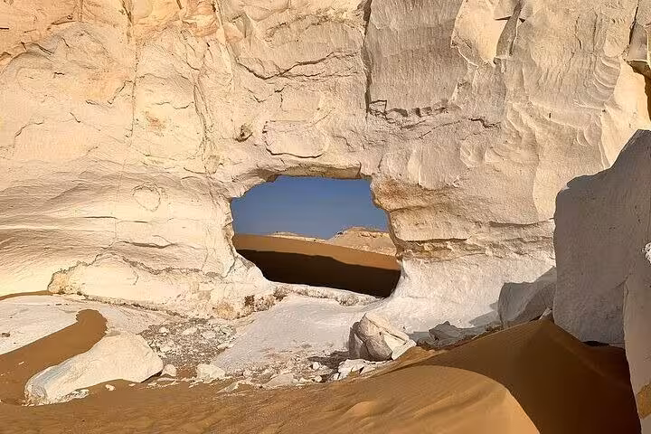 Natural rock arch in Egypt’s White Desert with golden dunes, a highlight stop on the White & Black Desert 2-day tour