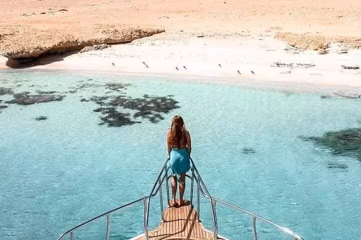 Woman on yacht bow above turquoise lagoon at White Island, Ras Mohammed boat tour from Sharm El Sheikh