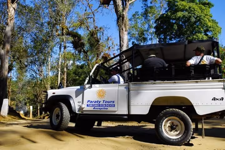 White jeep with Paraty Tours logo navigating lush forest trails on a private tour, offering an eco-friendly adventure.