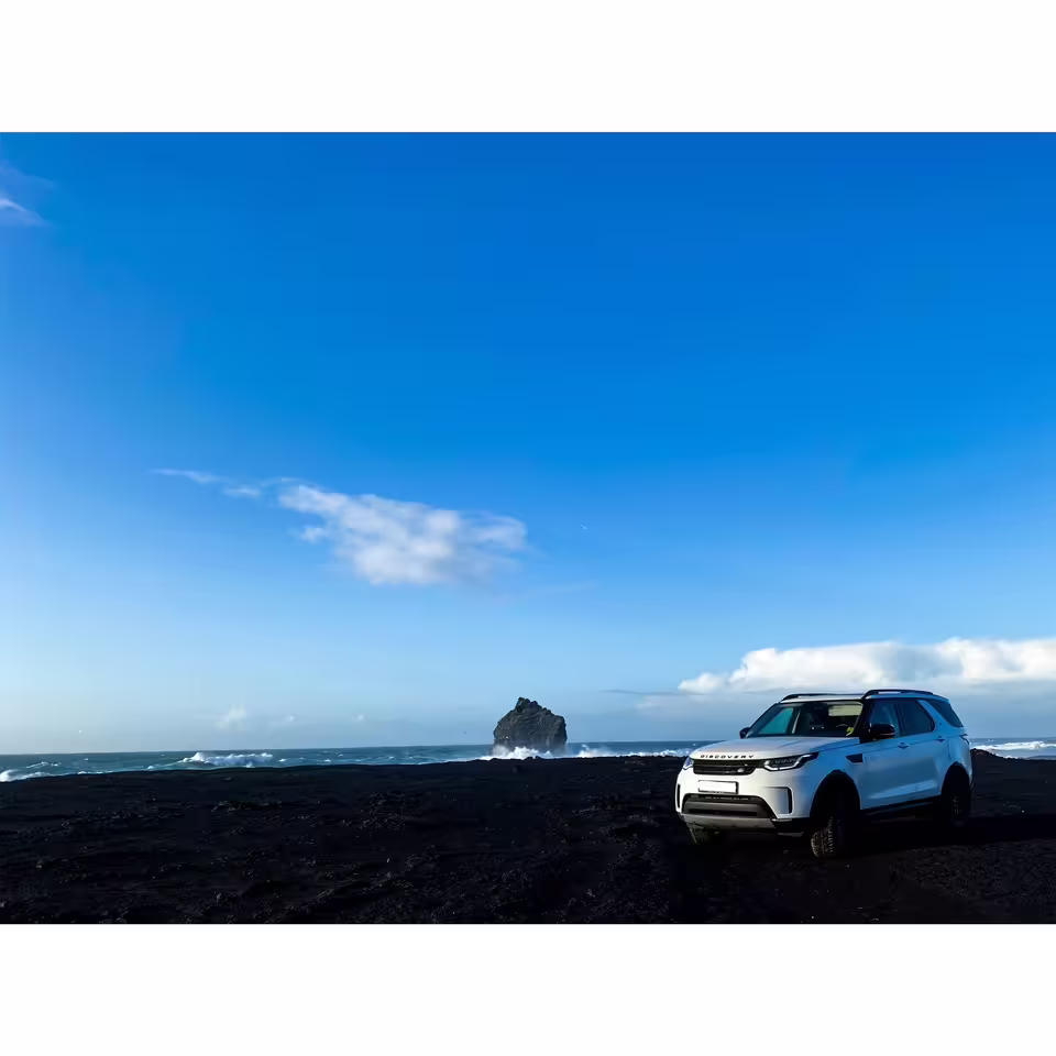White Land Rover Discovery luxury SUV parked on Iceland black sand beach for private Reykjavik group transfer