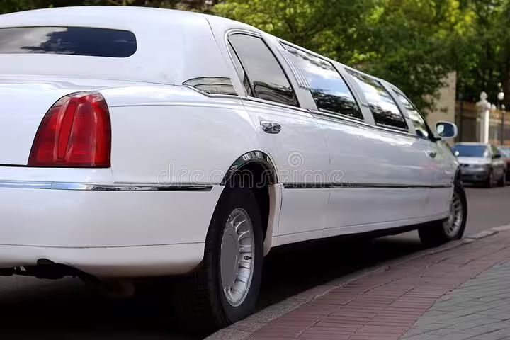 White stretch limousine parked on a city street for private airport transfer