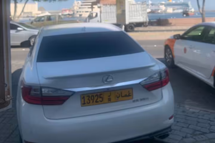 Sleek white luxury car with Omani license plate, exemplifying premium travel options in Muscat.