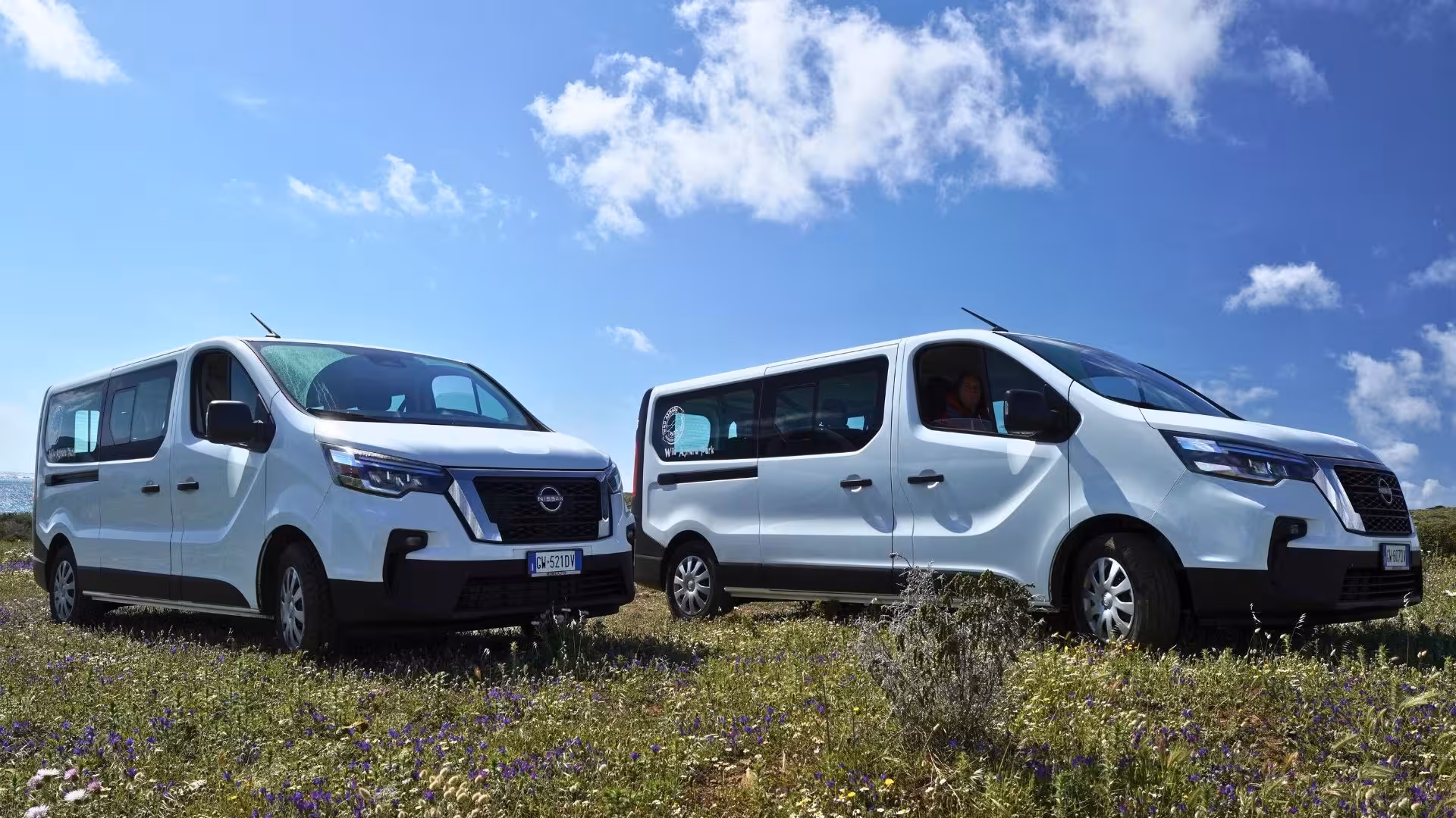 Two white minivans ready for an Asinara island tour, offering a comfortable journey through Sardinia's natural beauty.