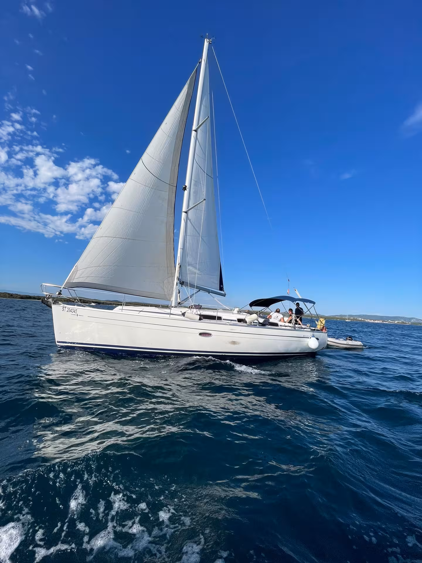 White sailboat cruising on deep blue sea under clear sky, perfect Sailing Adventure tour with skipper