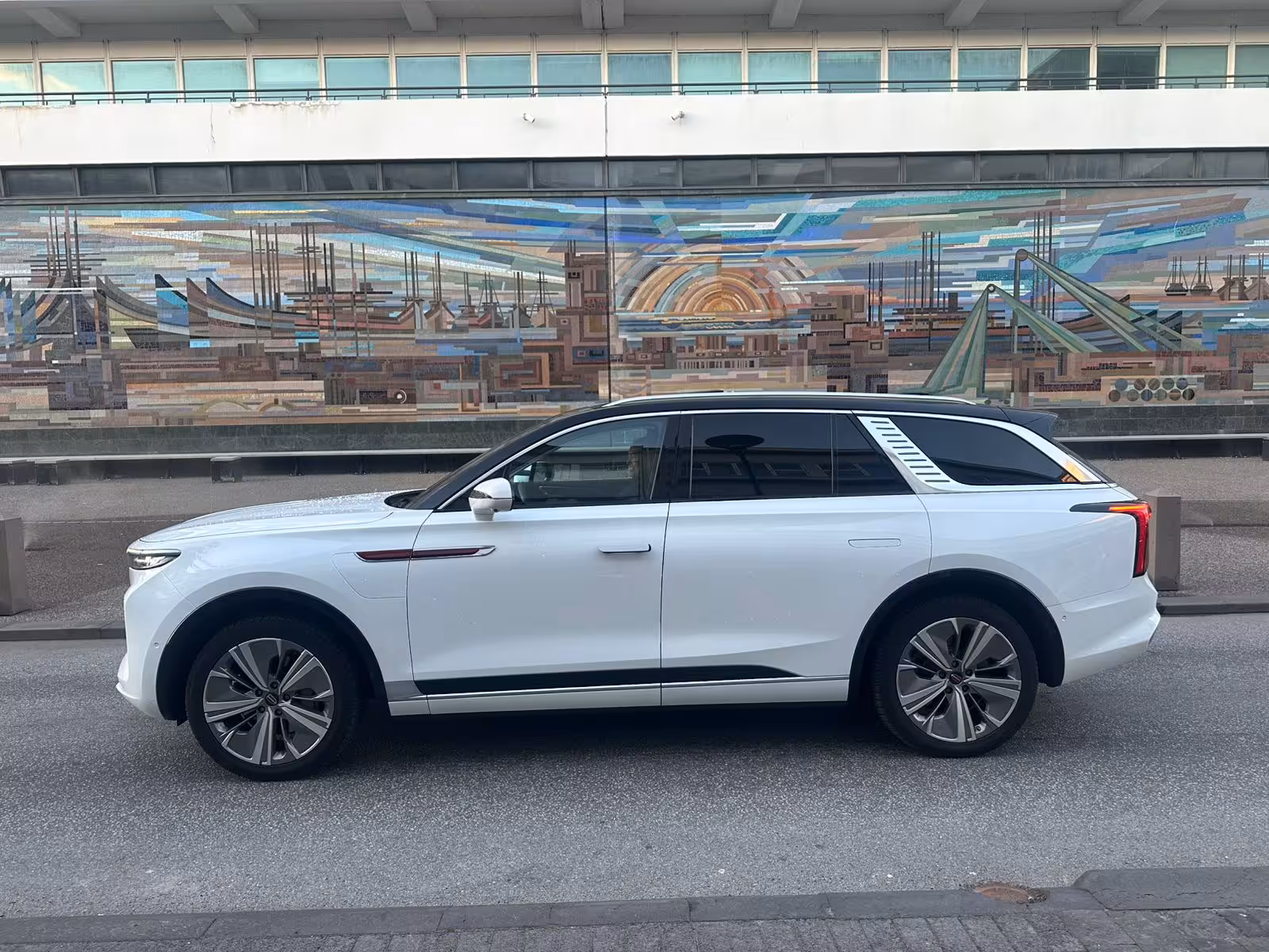 White luxury SUV parked at Reykjavik cruise port terminal with colorful mosaic mural backdrop