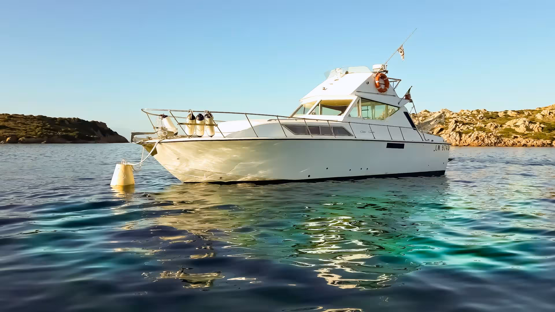 Close-up of a white tour boat anchored in the serene waters of La Maddalena, Sardinia.