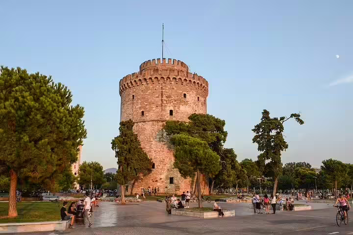 White Tower of Thessaloniki surrounded by visitors and lush greenery during a custom sightseeing layover tour.