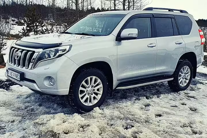White Toyota Land Cruiser Prado SUV parked on snow in Iceland for private airport transfer
