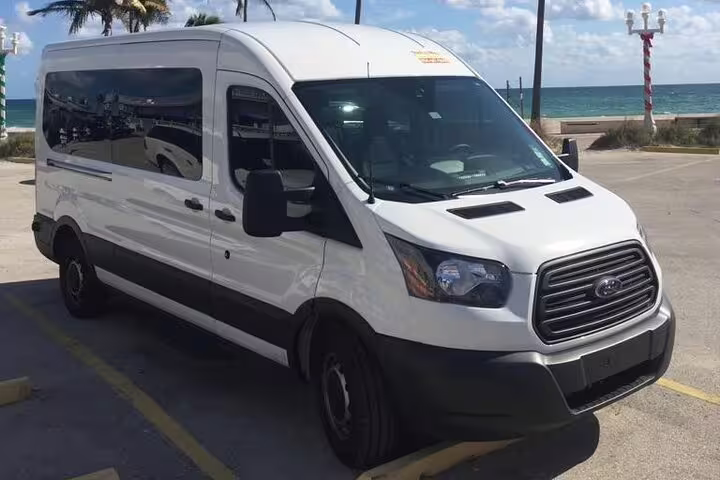 White Ford Transit van parked near beach for comfortable private transfer from Punta Cana to Puerto Plata.