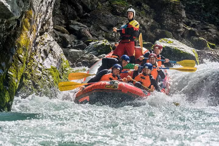 Group of rafters paddles through dynamic Engadin rapids on an exhilarating whitewater adventure.