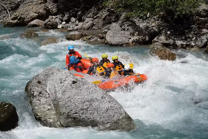 Exciting whitewater rafting experience in Engadin with paddlers maneuvering around rocks in a rapid-filled river.