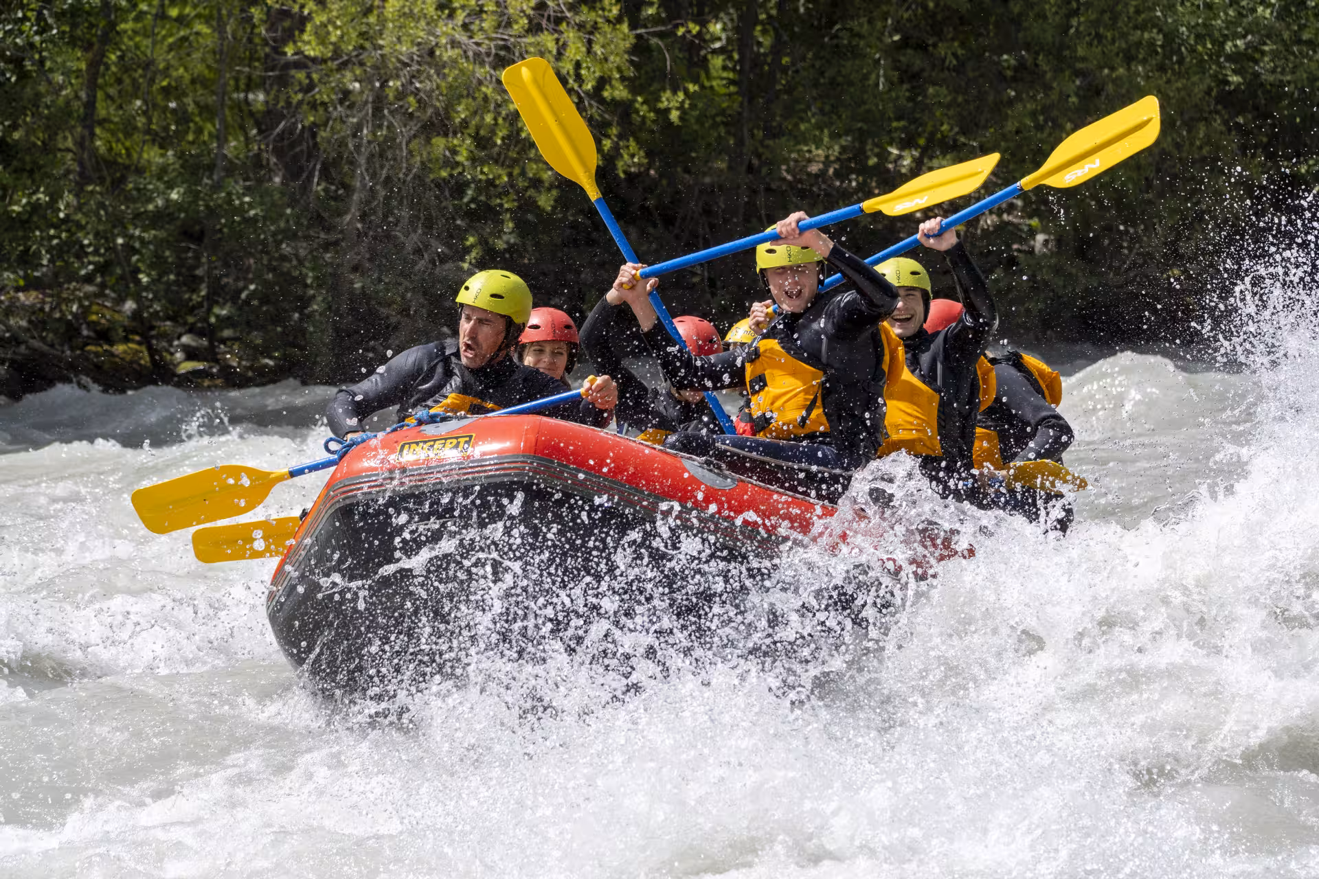 Excited rafters tackle challenging waves on the Inn River's Whitewater Action Tour in the scenic Engadin region.