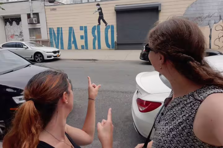 Two women pointing at a DREAM street art mural in Williamsburg Brooklyn