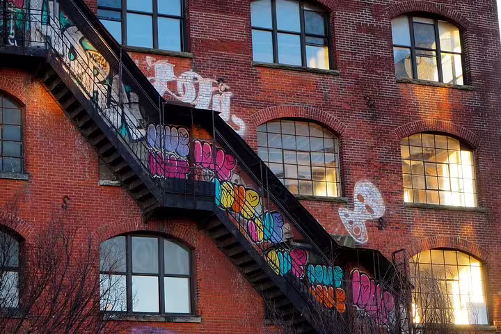 Colorful graffiti street art covering brick building exterior with black fire escape stairs in Williamsburg Brooklyn