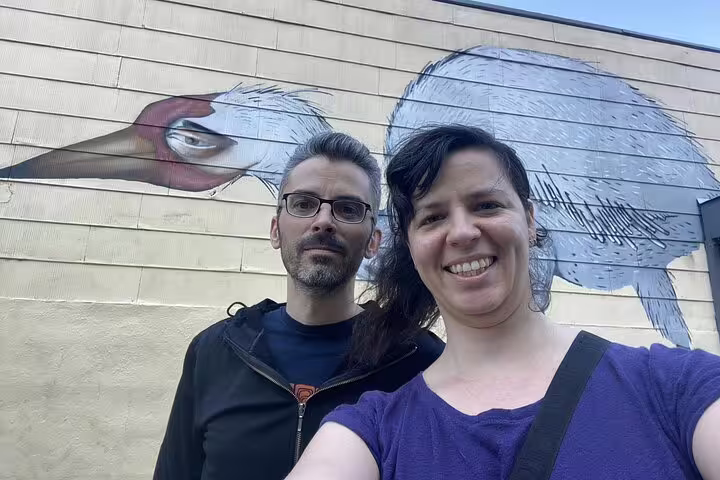 Couple smiling in front of large bird street art mural in Williamsburg Brooklyn