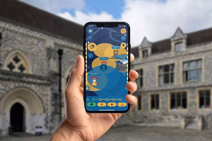 Hand holding smartphone with GPS walking tour app in front of historic Winchester Cathedral stone building