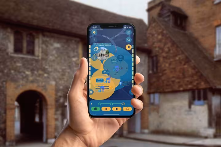 Hand holding smartphone with GPS navigation app map for self-guided walking tour near Winchester historic stone buildings