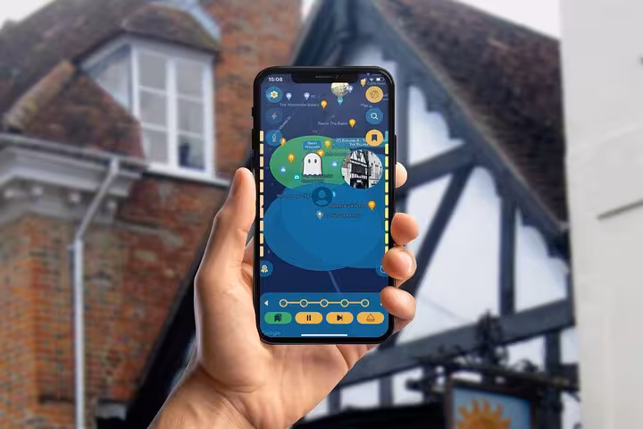 Hand holding smartphone displaying GPS app map for self-guided walking tour in Winchester historic city center