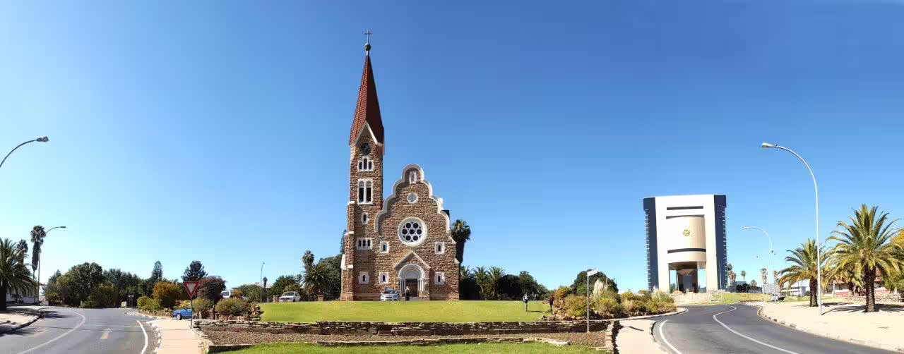 Historic church and modern building in Windhoek under clear blue skies, perfect for Etosha Safari Adventure tours.