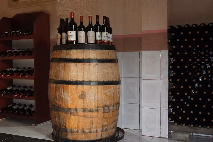 Wine bottles displayed on a wooden barrel in a cozy tasting room in Berat.