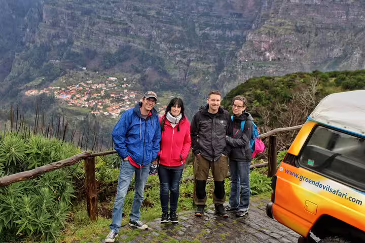 Travelers enjoying a scenic view at Cabo Girão during a Wine & Jeep Safari tour in Madeira, with lush landscapes and a safari vehicle nearby.