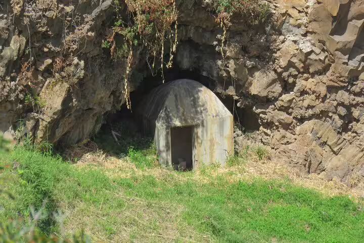 Entrance to a rustic wine cave nestled in rocky cliffs, highlighting the allure of a half-day jeep wine tour and sea cliff adventure.