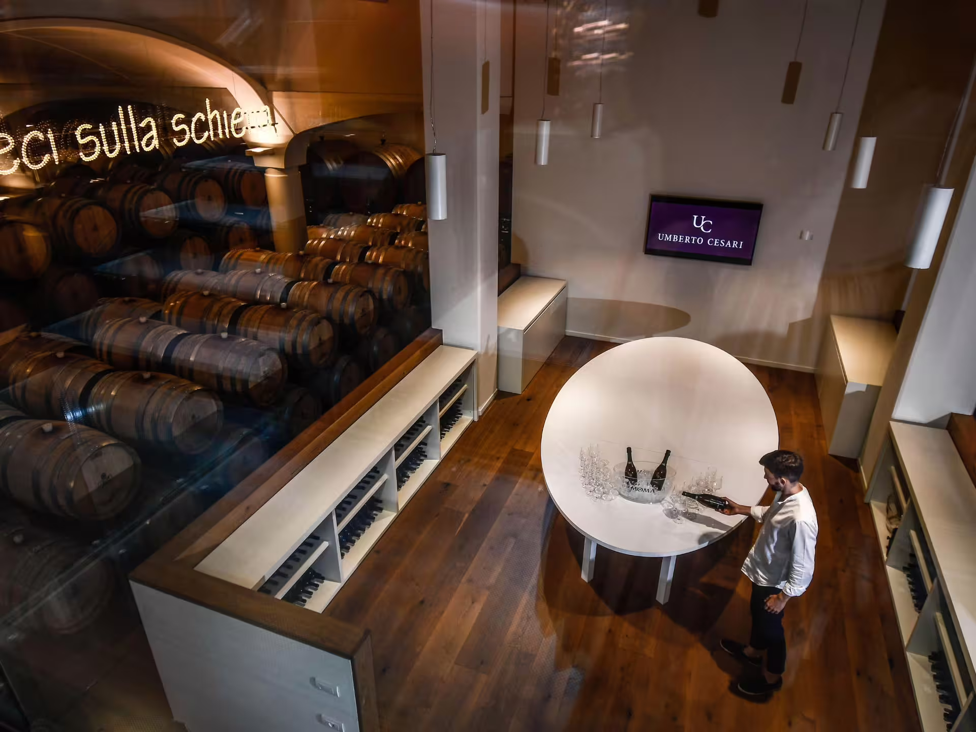 Wine cellar tour with barrels and tasting table at a winery near Bologna, featuring Umberto Cesari wines.