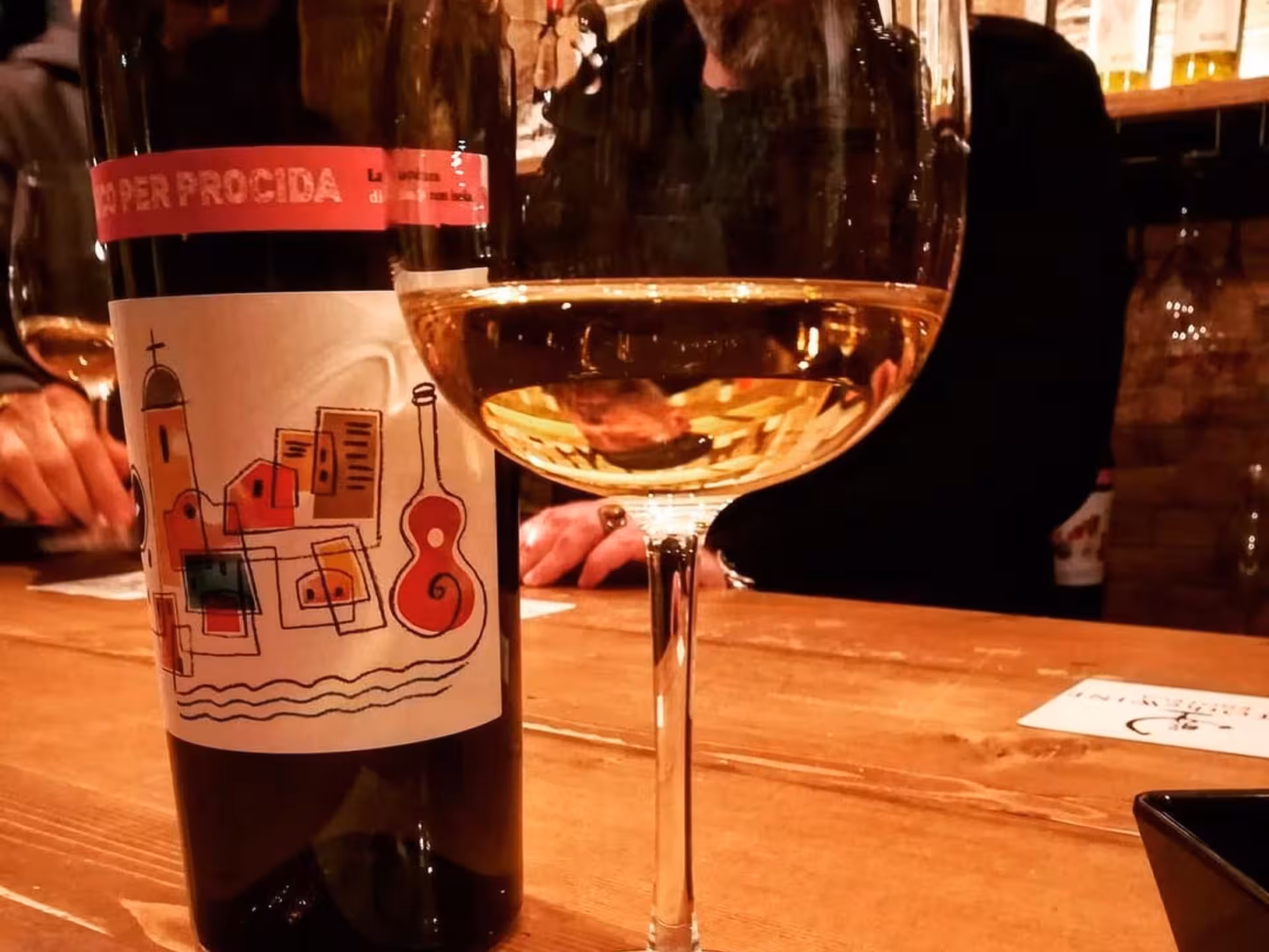 Close-up of a wine glass and bottle on a rustic bar during a wine tasting experience in Naples.