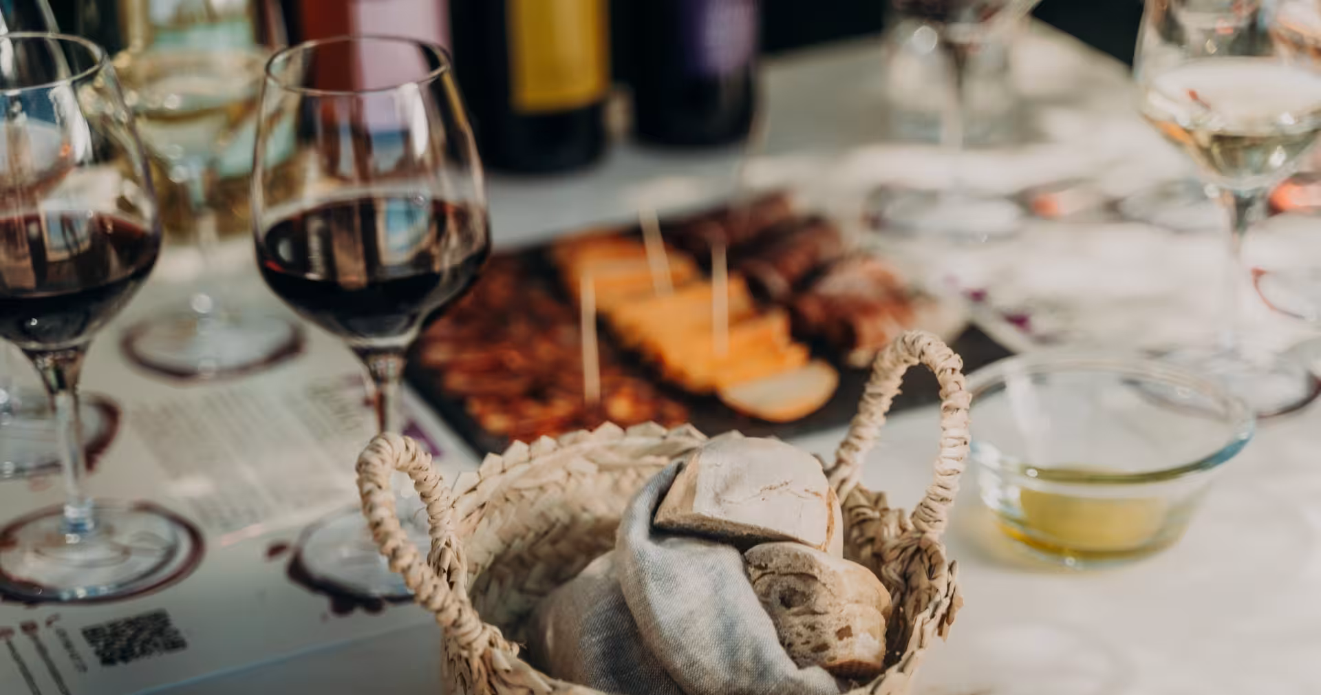 Gourmet wine and nature escape tasting table with red wine glasses, rustic bread basket, olive oil and local cheese platter