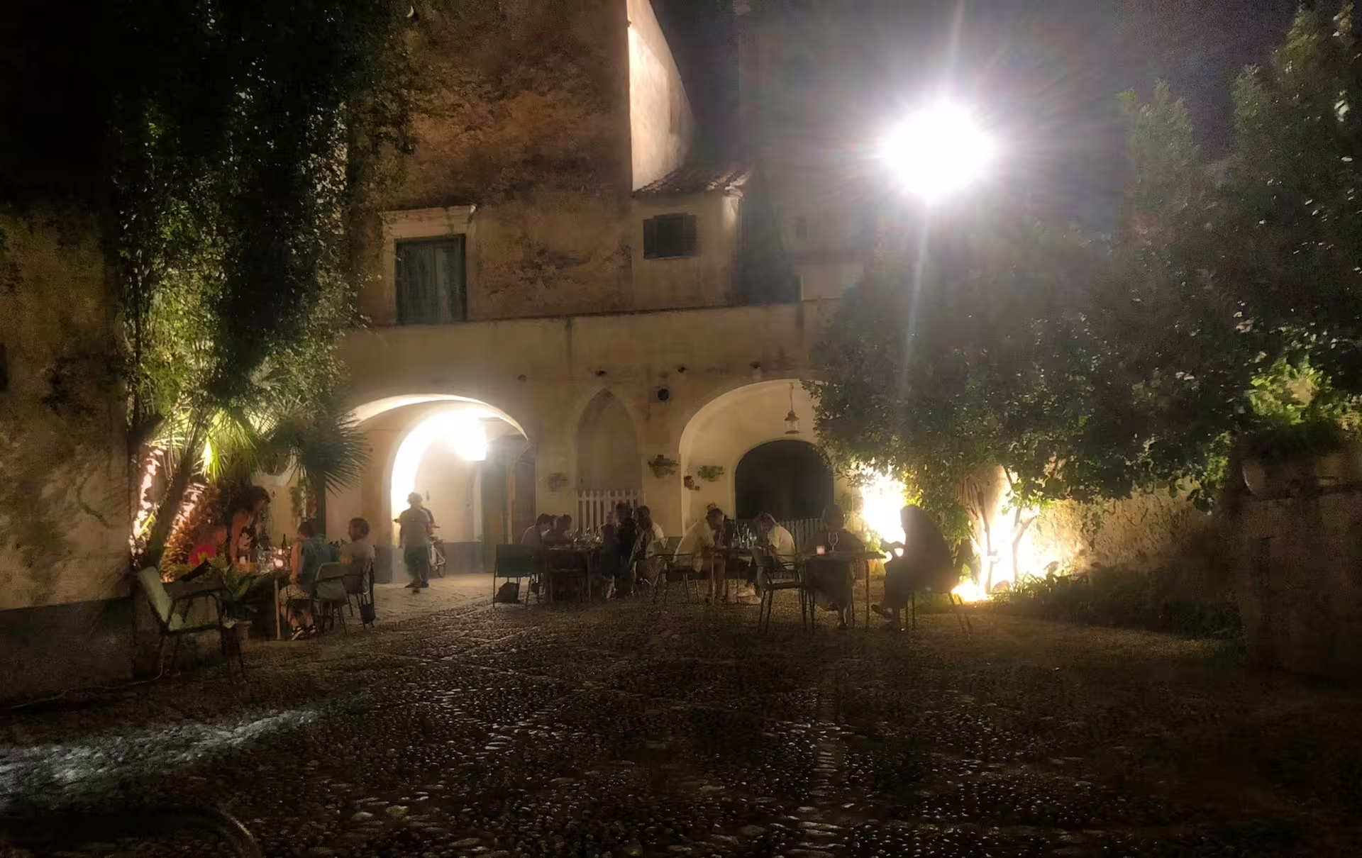 Guests enjoy an intimate candlelit dinner in a rustic stone courtyard after a wine tasting in Sant’Agata de’ Goti, Italy