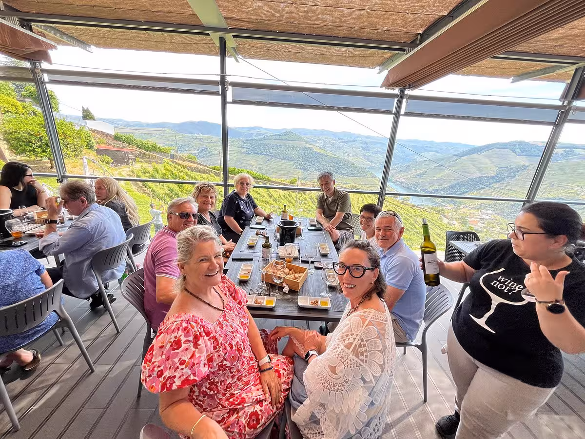 Wine tasting lunch with panoramic Douro Valley views, group enjoying local wines on a terrace overlooking vineyards