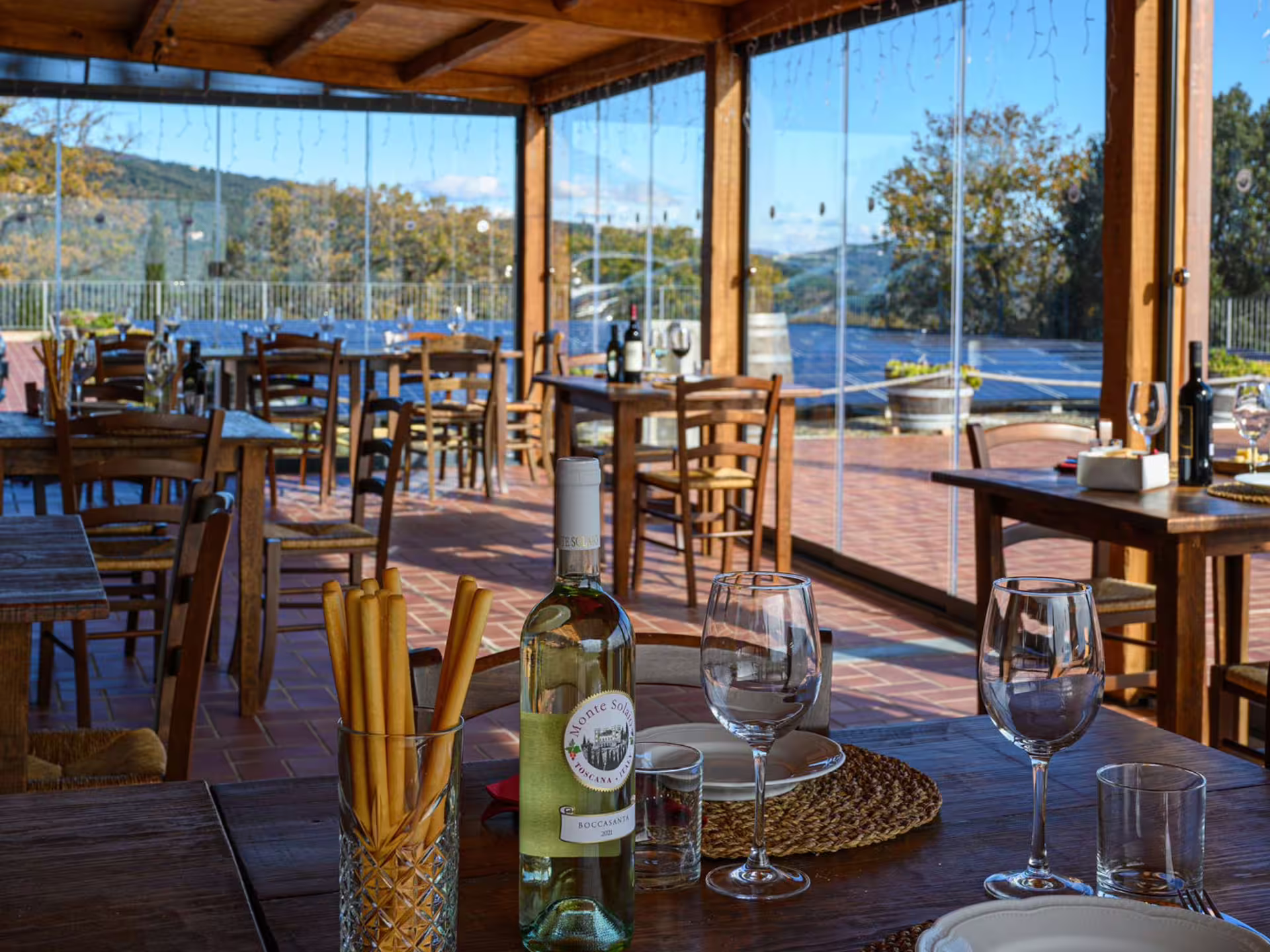 Cozy indoor dining with wine bottles and glasses set against panoramic vineyard views near Livorno, perfect for tastings.