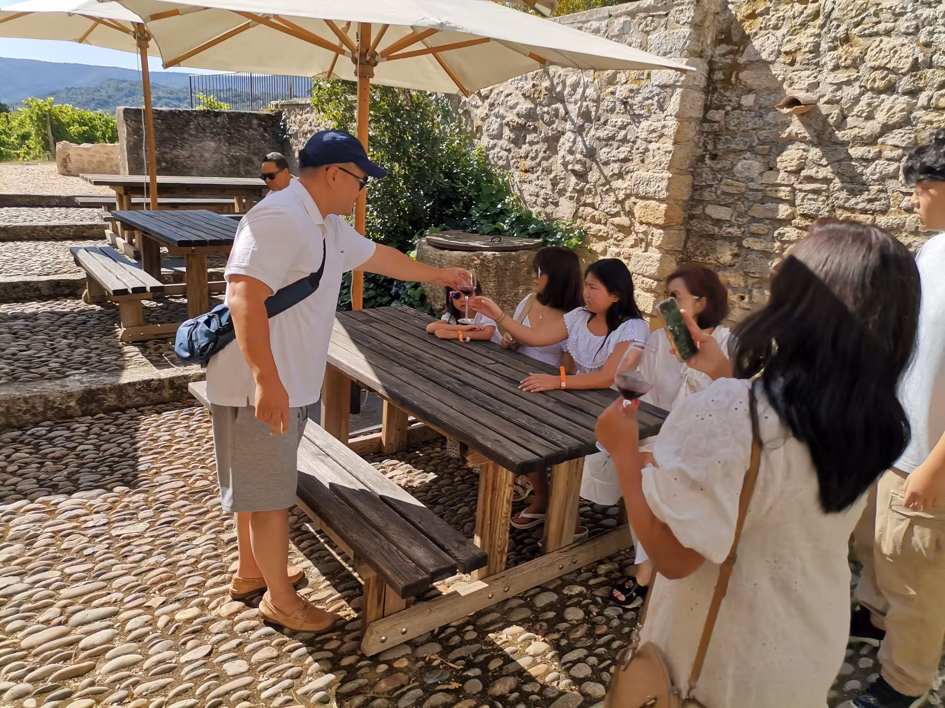 Outdoor wine tasting stop during lavender field experience, group sampling local rosé at a rustic Provence terrace