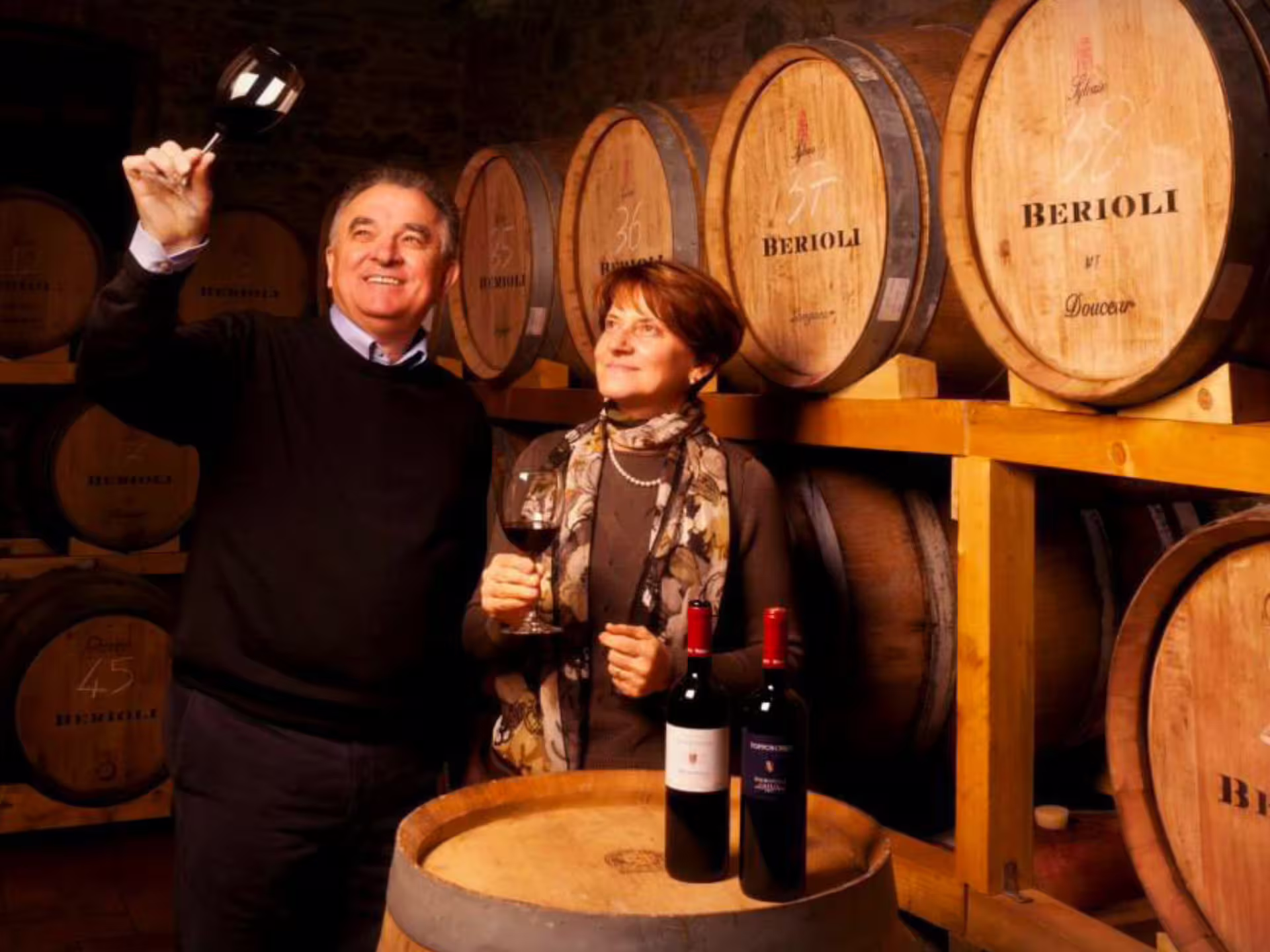 Wine tasting in Perugia cellar near Lake Trasimeno, guests with red wine beside oak barrels and bottles