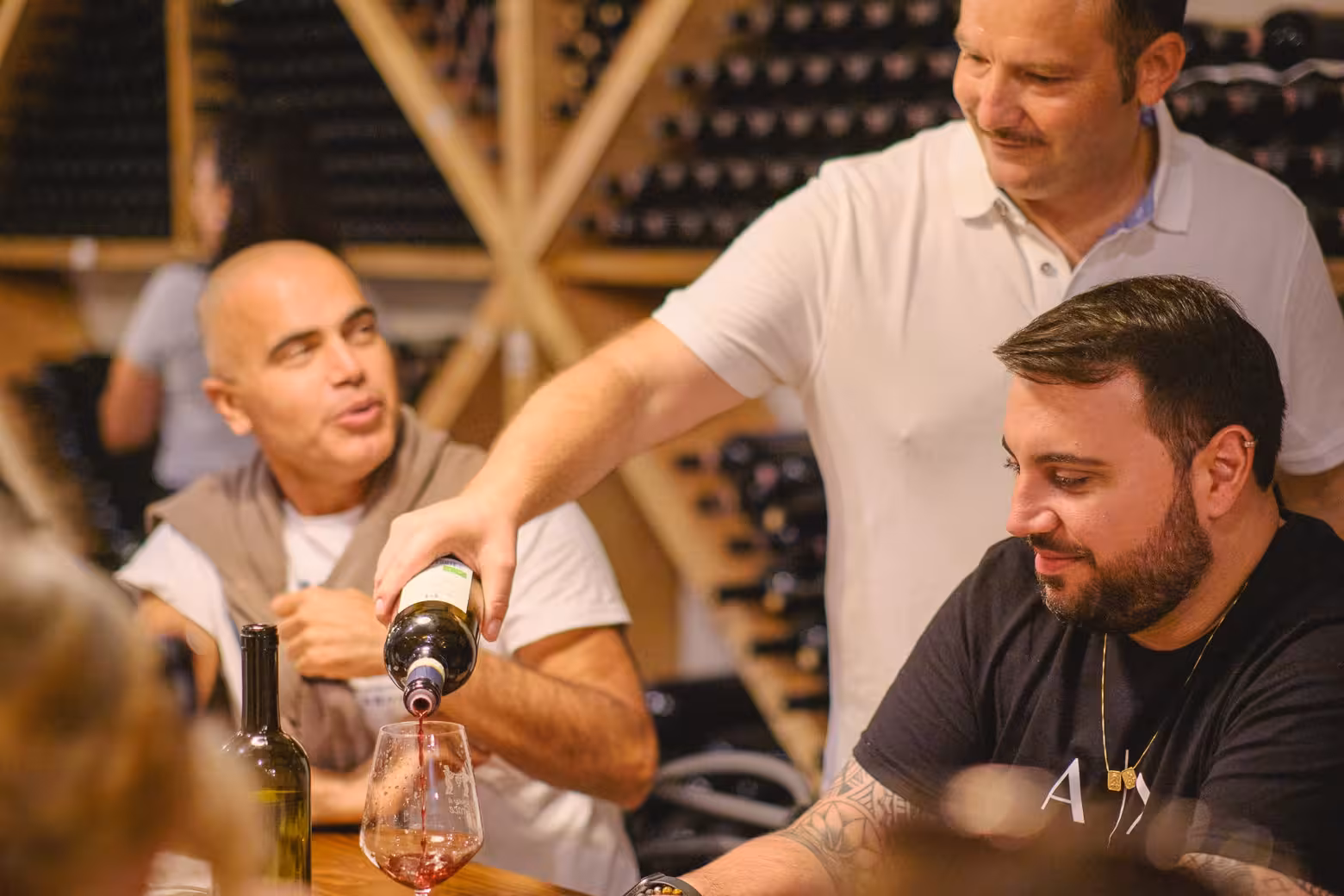 Small group enjoying wine tasting session with expert guidance in a cozy wine cellar setting.